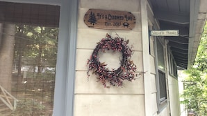 A wooden sign with a wreath and a welcome sign on a house's exterior wall.