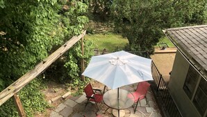 A patio area with a round table and four chairs, an umbrella, and a wooden pergola.