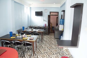 Uma sala de jantar com piso estampado, um relógio na parede e um bebedouro.