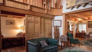Un vaste espace de vie agrémenté d’un canapé en cuir vert, de meubles en bois et d’une grande porte en bois.