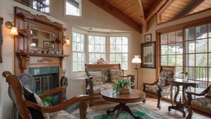Une pièce chaleureuse avec une cheminée, des meubles en bois et de grandes fenêtres.