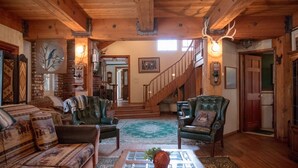 Un intérieur rustique avec un escalier en bois, des fauteuils en cuir et une cheminée.