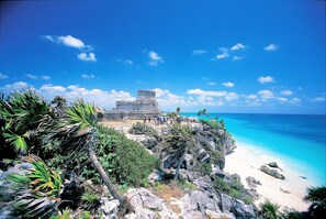 Ein Küstenblick mit blauem Himmel, Sandstrand und einer Steinstruktur.