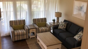 A living room with striped armchairs, a dark sofa, a wooden coffee table, and a lamp on a side table. - 3 Bedroom, 3 Bath Oceanside Beach Villa (Hilton Head Island)