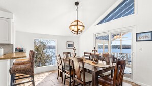 A dining area with a large table, chairs, and a hanging light fixture. - Margaritaville Resort~ Close to the Pool~ Large Home-Amazing Water Views-Recently Redecorated (Osage Beach)