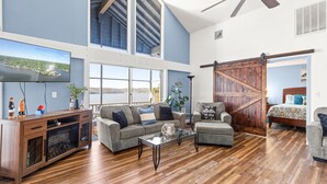 A spacious living room with a large TV, wooden flooring, and a cozy seating area. - Margaritaville Resort~ Close to the Pool~ Large Home-Amazing Water Views-Recently Redecorated (Osage Beach)