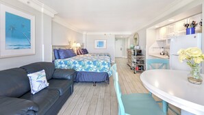 Una camera d'albergo compatta con un letto, un divano, un tavolo da pranzo e angolo cottura.