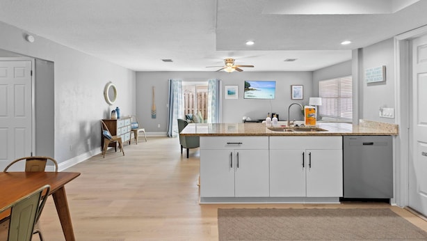 A modern kitchen with white cabinets, a granite countertop, and a built-in dishwasher. - Cozy Beach House ( Walking Distance to Beach) (New Smyrna Beach)