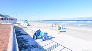 A beach with a building, beach chairs, and umbrellas. - Cozy Beach House ( Walking Distance to Beach) (New Smyrna Beach)