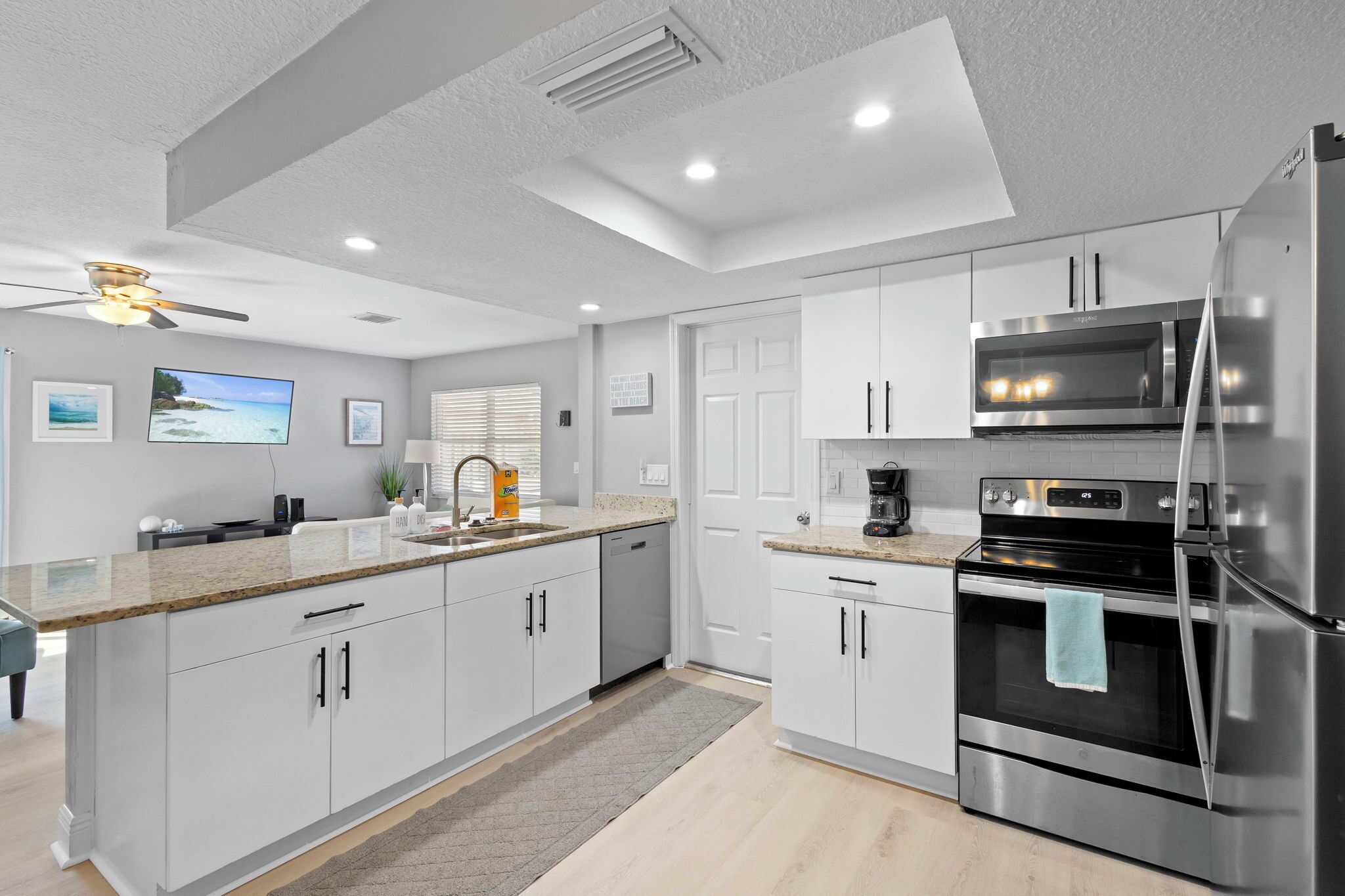 A modern kitchen with white cabinets, stainless steel appliances, and a large island with a sink.