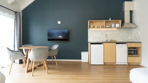 A modern kitchen with a dark blue accent wall, wooden cabinets, and a built-in microwave. - Mt. Wellington Motel (Auckland)