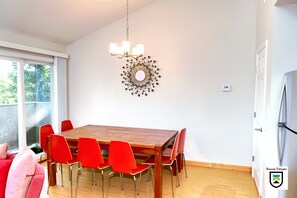 A dining area with a wooden table and red chairs, a chandelier, and a decorative wall piece.