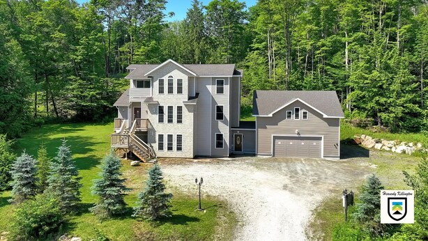 A two-story house with a large front yard, a garage, and a driveway leading to the main entrance.