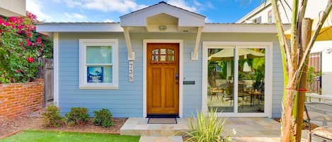 Une maison à deux étages avec une porte d’entrée, un petit porche et un espace patio.