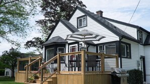 Une maison à deux étages avec une terrasse en bois, un barbecue et une cheminée.