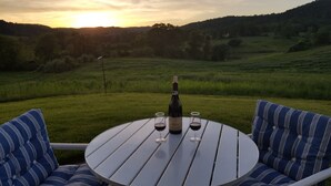 A round table with two chairs, a bottle of wine, and two glasses on it, set against a backdrop of a grassy field and a sunset. - Weekend getaway short distance from DC/Northern Virginia (Markham)
