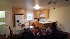A compact kitchen with wooden cabinets, a refrigerator, microwave, and a dining area with a table and chairs. - Weekend getaway short distance from DC/Northern Virginia (Markham)