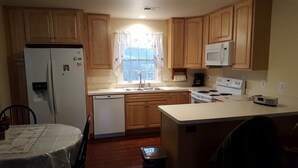 A kitchen with wooden cabinets, a refrigerator, a microwave, a stove, and a sink. - Weekend getaway short distance from DC/Northern Virginia (Markham)
