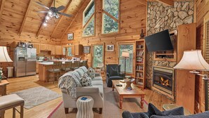 A cozy cabin interior with a kitchen, dining area, living room, and fireplace. - Dancing Bears | Hot Tub | Grill (Morganton)