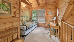 A cozy cabin interior with a bed, a desk, and a chair. - Dancing Bears | Hot Tub | Grill (Morganton)