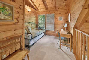 Ein gemütliches Blockhaus-Interieur mit einem Bett, einem Schreibtisch und einem Sessel.