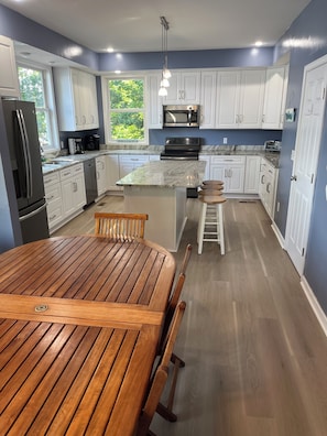 Une cuisine moderne avec des meubles blancs, un îlot central et une table à manger en bois.