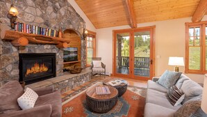 Una sala de estar acogedora con chimenea de piedra, techo de madera y un espacio de descanso confortable.