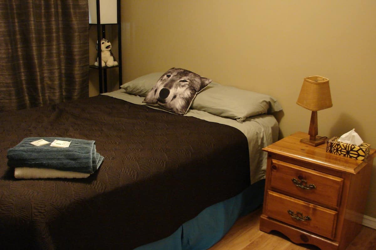 Un dormitorio con una cama, una mesita de noche, una lámpara y un espejo.