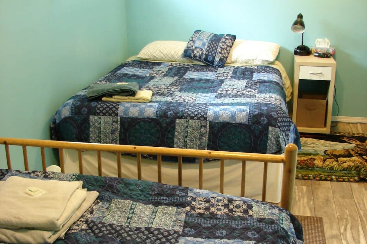 Un dormitorio con dos camas, una mesita de noche y un ventanal.