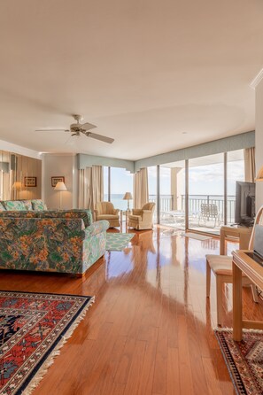 Ein geräumiges Wohnzimmer mit einer großen Couch, einem Fernseher und einem Balkon mit Meerblick.