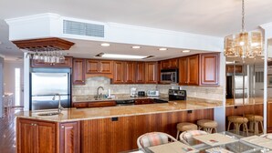 A spacious kitchen with wooden cabinets, a large island, and a glass dining table. - Surfmaster - Oceanfront 3 Bedroom/3 Bath  Beautiful!!! Great Rates!! (Garden City)