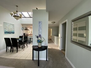 A dining area with a black table and chairs, a vase with flowers, and a wall-mounted sign that reads "BEACH".