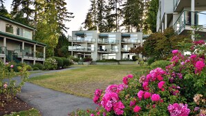 A multi-story residential building with a covered outdoor area and a pathway leading to it. - Oceanfront 2 bedroom Condo w/Stunning Views~Heated Pool/Hot Tub/Dock (Nanaimo)