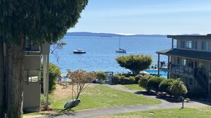 A coastal view with a pathway leading to a building with a balcony overlooking the sea. - Oceanfront 2 bedroom Condo w/Stunning Views~Heated Pool/Hot Tub/Dock (Nanaimo)