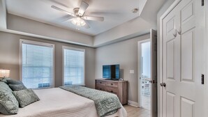 Een slaapkamer met een bed, een plafondventilator, een dressoir en een televisie.