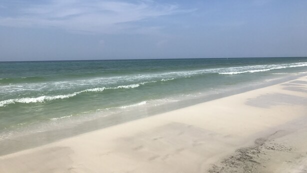 Een strand met heldere lucht en rustige golven.