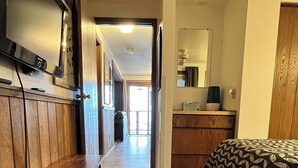 A hallway leading to a bedroom with a bed, a bench, a TV, and a dresser. - 2 Bedroom 2 Bathroom Condo - Base Area - Three Seasons (Mount Crested Butte)
