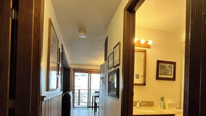 A hallway with wooden flooring, a wooden door frame, and a bathroom with a sink and toilet visible. - 2 Bedroom 2 Bathroom Condo - Base Area - Three Seasons (Mount Crested Butte)