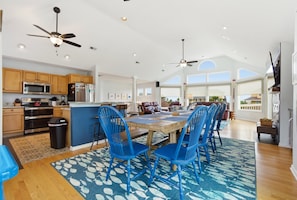 A spacious kitchen with wooden cabinets, a central island, and blue chairs.