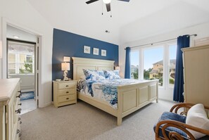 A bedroom with a bed, bedside table, dresser, and a window with curtains.