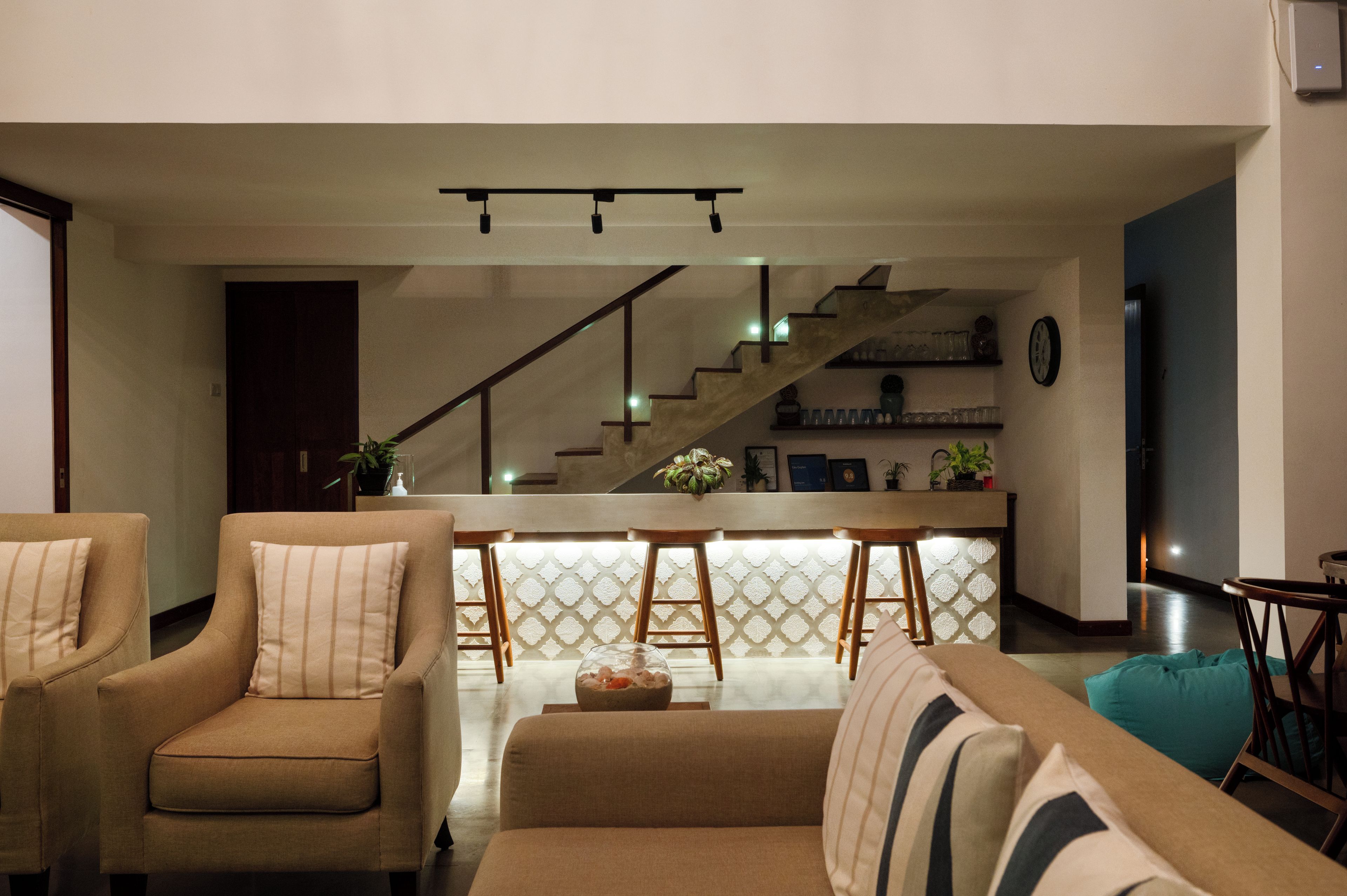 Una sala de estar moderna con un sofá, una mesa de centro y una zona de bar con taburetes.