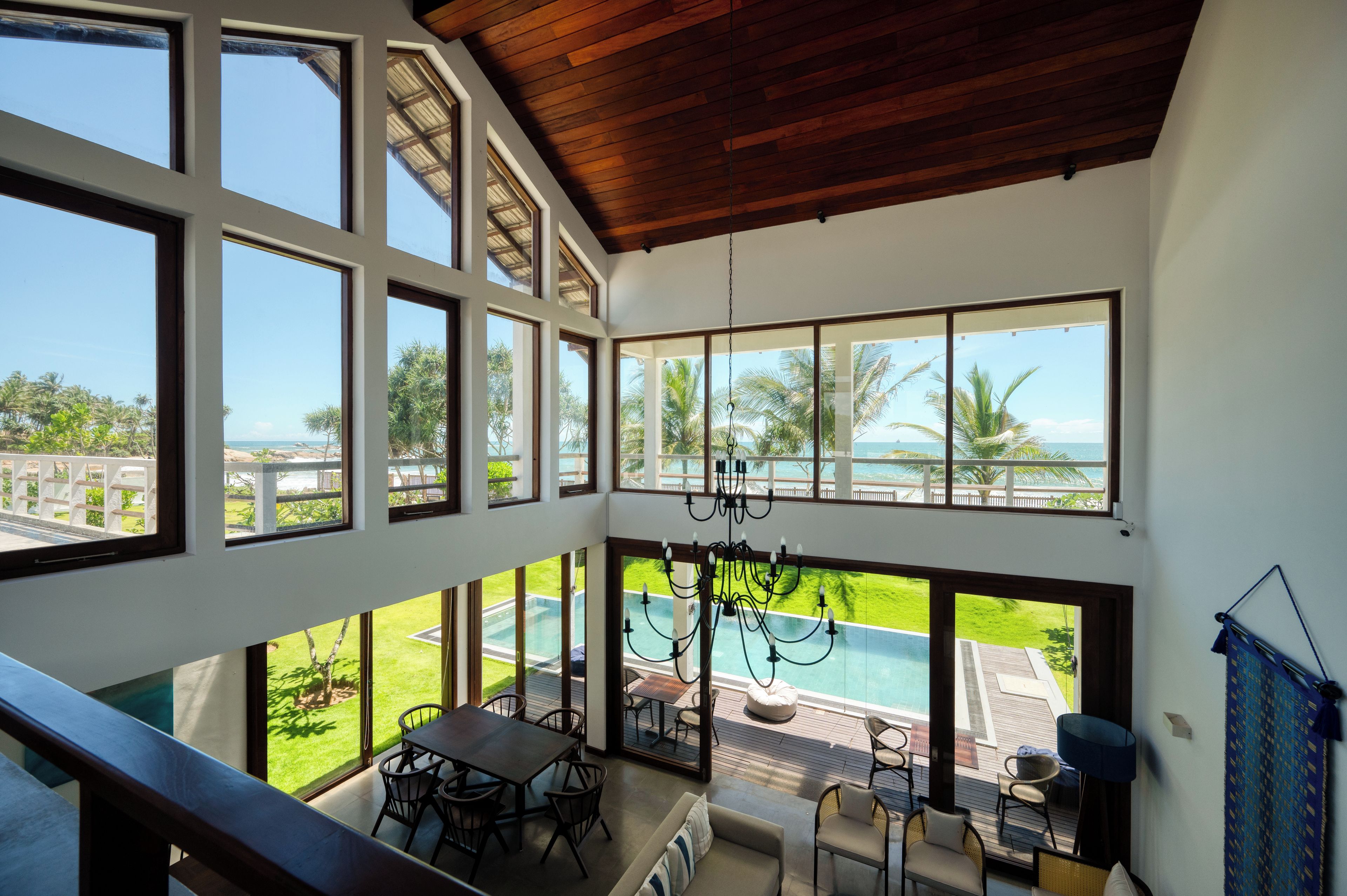 Amplia habitación con grandes ventanales que dan a una piscina y un jardín exuberante.
