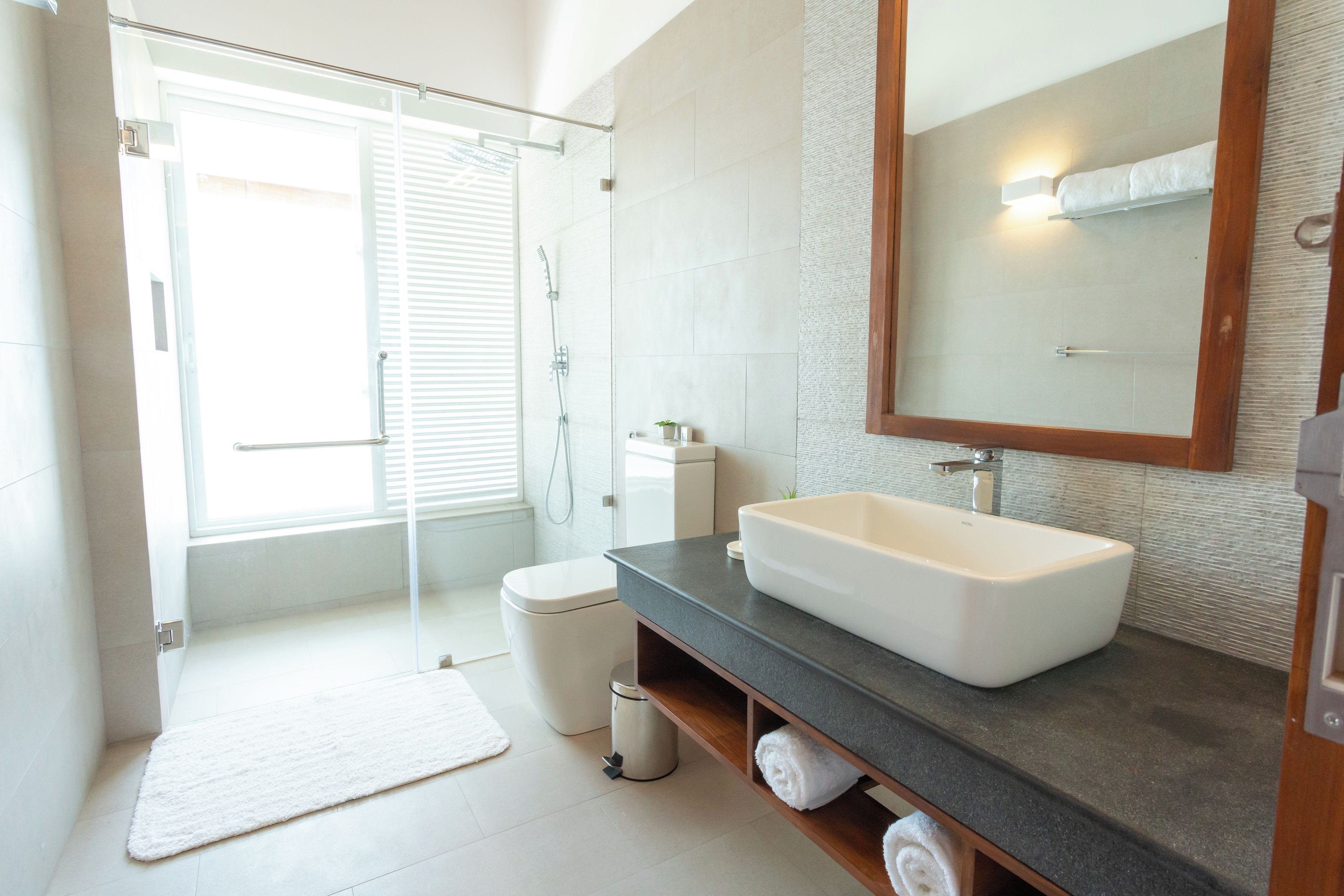 A modern bathroom with a walk-in shower, a large mirror, and a white sink.
