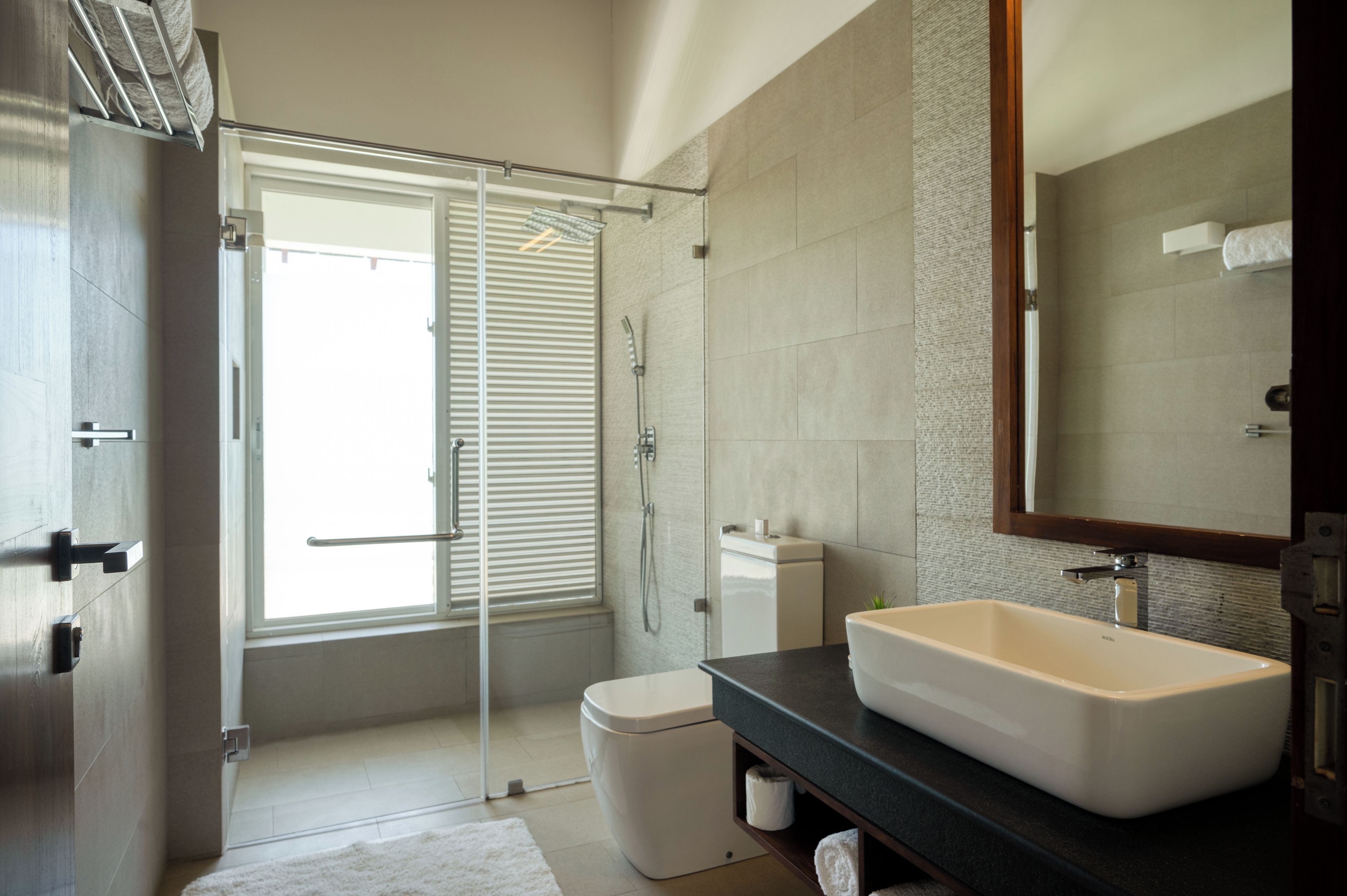 A modern bathroom with a walk-in shower, a toilet, a sink, and a large mirror.