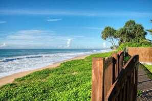 A beach with a wooden walkway, green vegetation, and the ocean. - Céu Ceylon (Kalametiya)