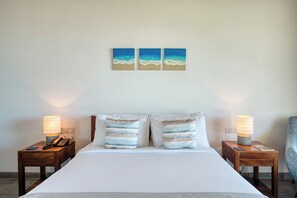 A hotel room with a bed, two bedside tables, lamps, and two wall-mounted paintings. - Céu Ceylon (Kalametiya)