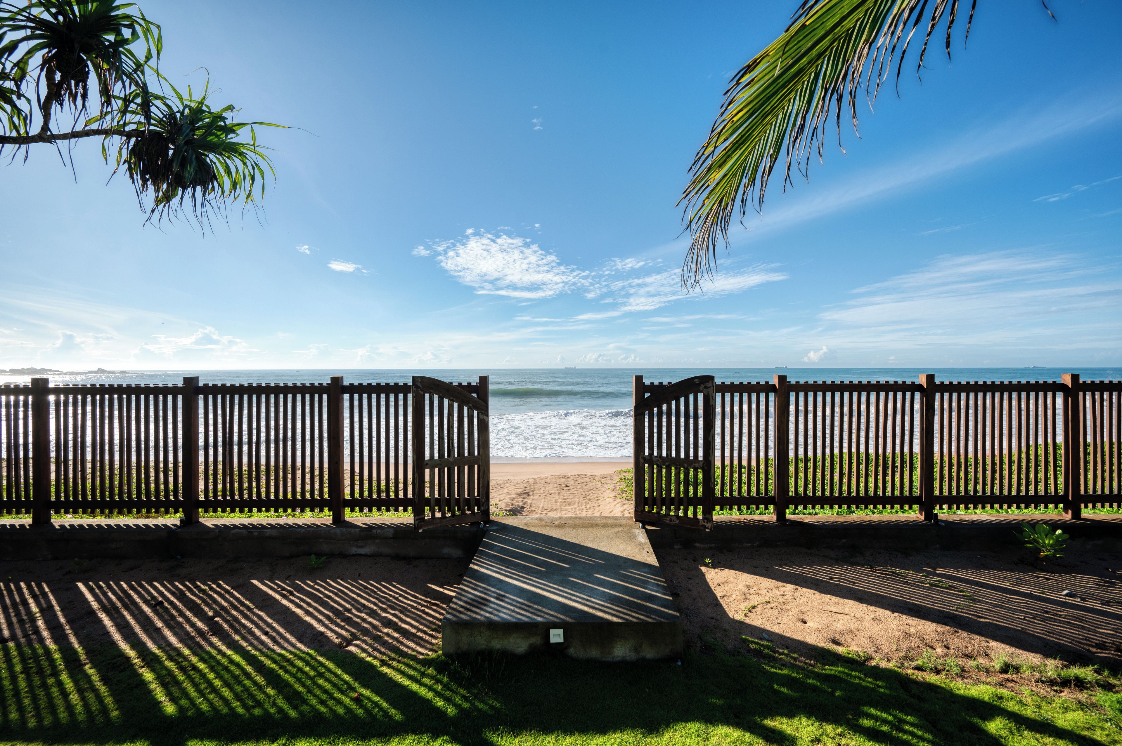 A wooden fence with a view of the beach and ocean.