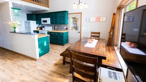 Une cuisine spacieuse avec des meubles de couleur turquoise, une table à manger en bois et un grand téléviseur.
