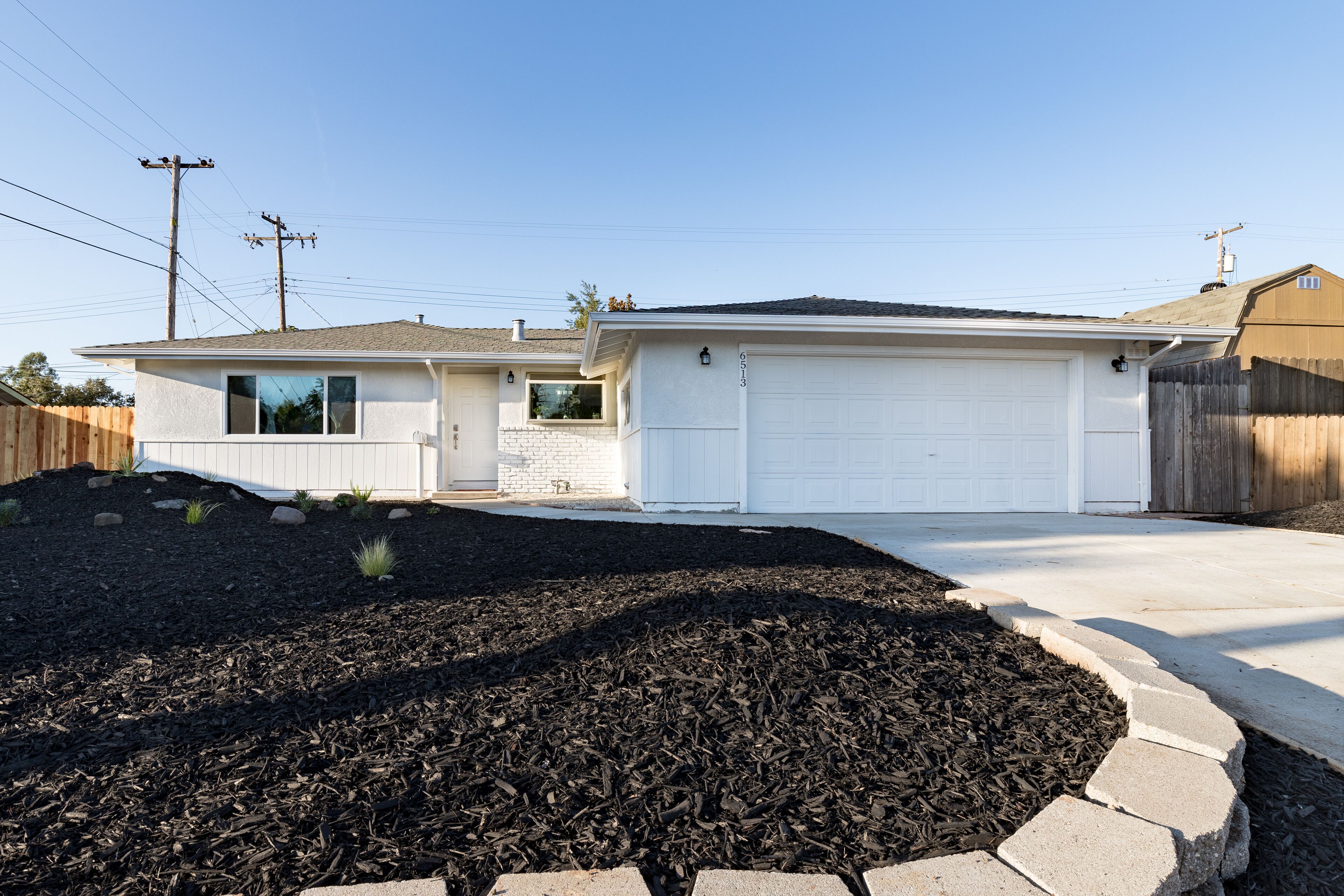 Une maison d’habitation avec un garage, une allée et un jardin aménagé.