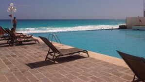 Un área junto a la piscina con sillones de descanso y vistas al océano.